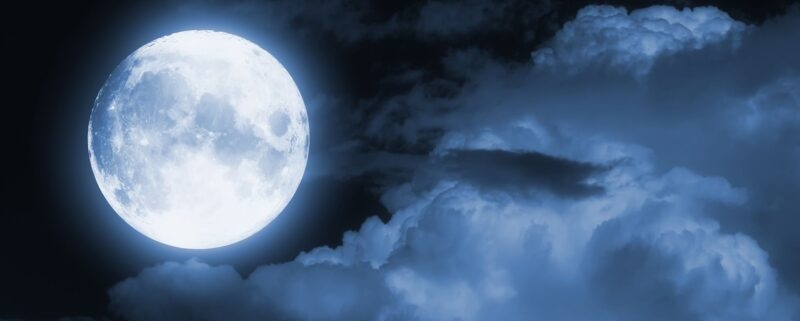 A full moon in a partly cloudy night sky.