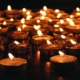 Countless small memorial candles that have been lit in a dark room.