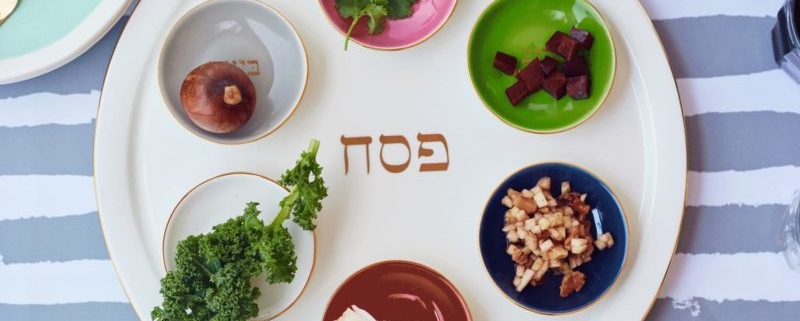 A seder plate on a blue and white striped tablecloth.